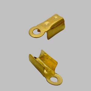 Peut inclure: Deux fermoirs en métal doré pour la fabrication de bijoux. Chaque fermoir a une boucle à une extrémité et une forme rectangulaire plate à l'autre extrémité.