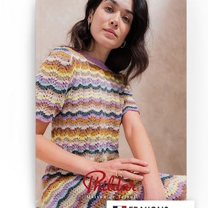 Op de afbeelding: Een vrouw draagt een kleurrijke, korte mouwen gehaakte top en rok. De top heeft een golfachtig patroon in tinten geel, paars, groen en bruin. De afbeelding bevat de tekst "Phildar" en "FRANÇAIS".