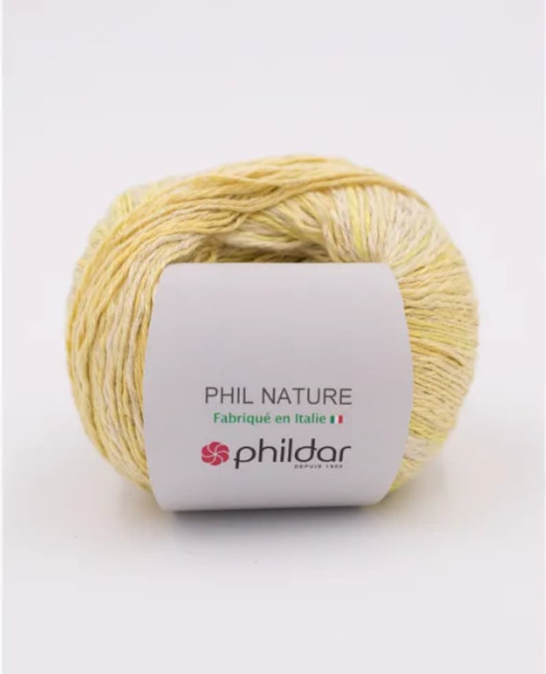 May include: A ball of yellow and white yarn with a label that reads "PHIL NATURE Fabriqu&eacute; en Italie" and a pink flower logo with the text "phildar DEPUIS 1903".