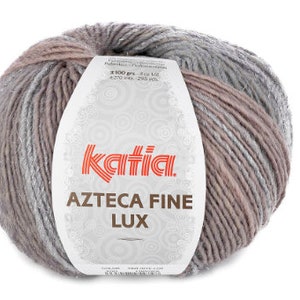 Könnte beinhalten: Ein Knäuel Katia Azteca Fine Lux Garn in einer hellbraunen und grauen Farbkombination. Das Garn besteht aus einer Mischung aus Alpaka und Wolle.