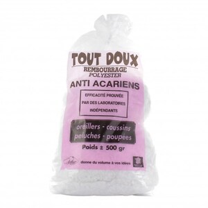 Op de afbeelding: Een transparante zak gevuld met witte polyester vulling. De zak heeft een roze label met de tekst "TOUT DOUX" en "ANTI ACARIENS". Het label geeft ook aan dat de vulling voor kussens, knuffels en poppen is, met een gewicht van ongeveer 500 gram.