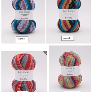 Könnte beinhalten: Vier Knäuel buntes Garn zum Stricken von Socken. Das Garn ist in verschiedenen Farben gestreift, darunter Rot, Blau, Grün, Gelb und Schwarz. Das Garn ist mit "PHIL SOCKS" und "phildar" gekennzeichnet. Das Garn heißt "cabrillo", "carmel", "matador" und "santa monica".