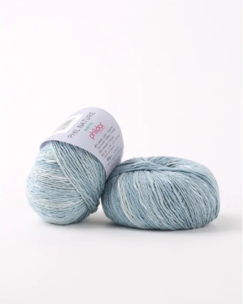 May include: Two balls of light blue yarn with white flecks. The yarn is labeled "Phil Nature" and "Phildar" with a pink logo.