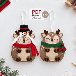 May include: Two felt deer ornaments with white hanging loops. One deer wears a black top hat and a red scarf, while the other wears a green scarf. Both have brown bodies, cream bellies, and pink cheeks. Text reads: PDF Pattern & Tutorial SVG.
