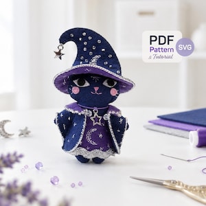May include: A dark blue felt cat doll wearing a matching pointed wizard hat and a purple dress with moon and star patterns. The hat and cape feature silver trim and small clear crystals. A silver star charm hangs from the hat tip.