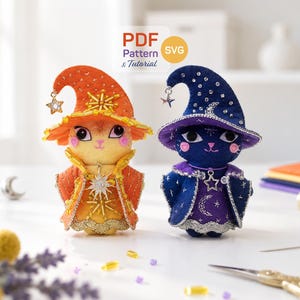 May include: Two plush cat figures wearing wizard hats and capes. The left cat is orange and yellow with sun-themed beadwork. The right cat is dark blue and purple with moon and star embroidery. A PDF Pattern & Tutorial label is visible above.