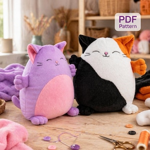 Puede incluir: Dos juguetes de peluche con forma de gato, uno lila y rosa, el otro negro, blanco y naranja. Los juguetes tienen caras sonrientes y están sobre una superficie de madera. La imagen también incluye suministros de costura y una etiqueta de patrón PDF.