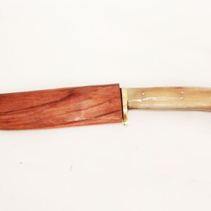 May include: A wooden-handled knife with a brown wooden sheath. The handle is made of bone and has a light brown color. The blade is not visible in the image.