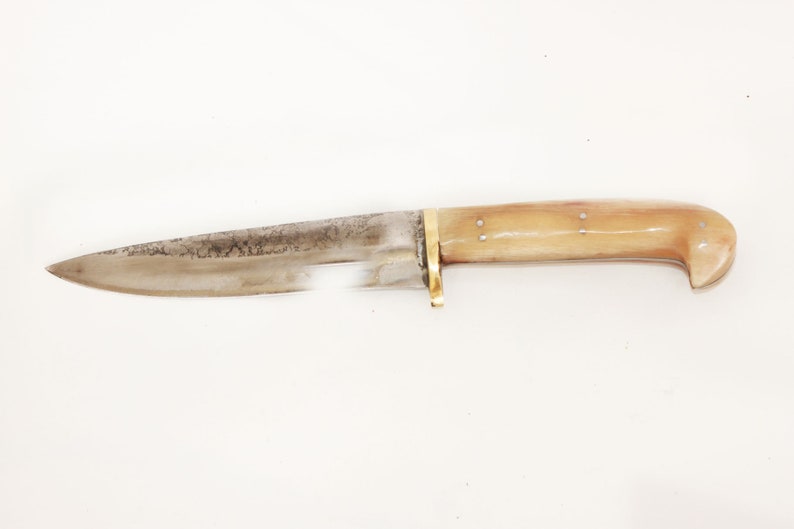 May include: A vintage hunting knife with a bone handle and a brass guard. The blade is made of steel and has a slight curve.
