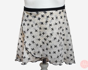 Può includere: Una gonna da ballo in tulle beige con elastico in vita nero e fiocchi in velluto nero. La gonna ha un orlo a balze.