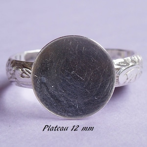 Può includere: Anello in argento con una montatura rotonda da 12 mm. La fascia dell'anello presenta un motivo floreale decorativo.