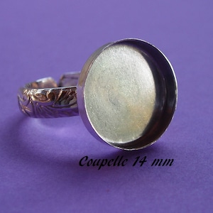 May include: Silver ring with a 14 mm round bezel setting. The ring band has a floral design.