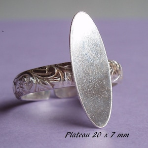 Peut inclure: Bague en argent avec un dessus ovale plaqué argent. La bague a un design orné et le dessus mesure 20 mm sur 7 mm.