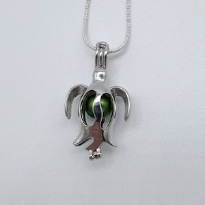 May include: A silver turtle charm necklace with a green glass bead inside. The necklace is on a silver chain.