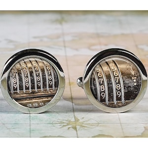 May include: A pair of silver cufflinks with a vintage-style image of a mechanical cash register with numbers 5, 6, 7, 8, and 9.