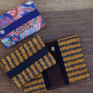 May include: Two fabric card holders with elastic closures. The first holder has a blue background with a colorful floral pattern and the text "10". The second holder has a brown background with a black geometric pattern and the text "11".