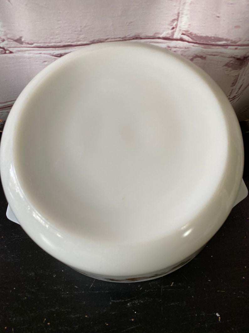 May include: White ceramic baking dish with a round bottom and a slightly flared rim. The dish is empty and appears to be new.