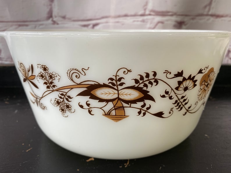 May include: White ceramic mixing bowl with a brown and white floral design. The bowl has a rounded shape and a wide rim.