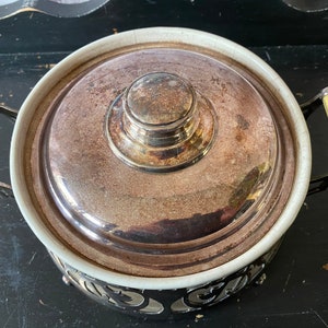 K&ouml;nnte beinhalten: Eine silberne Chafing Dish mit einer wei&szlig;en Porzellan-Innenauskleidung und einem dekorativen Metallsockel. Der Deckel hat einen silbernen Knopf und ist leicht ge&ouml;ffnet.