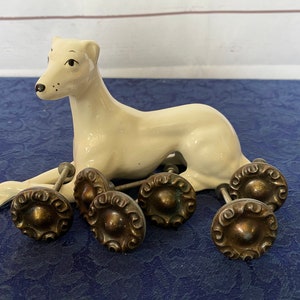 May include: A white ceramic figurine of a dog with seven antique brass cabinet knobs with intricate designs.