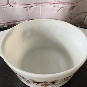 May include: White ceramic baking dish with a brown floral pattern. The dish has two handles on the sides.