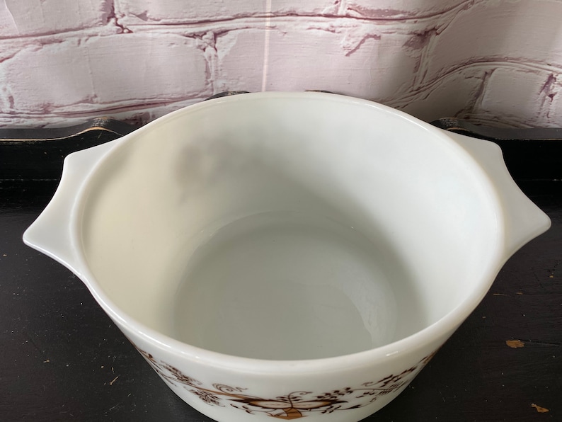 May include: White ceramic baking dish with a brown floral pattern. The dish has two handles on the sides.