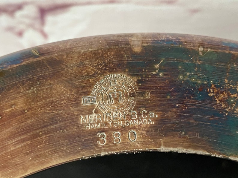 K&ouml;nnte beinhalten: Nahaufnahme eines silberfarbenen Metallobjekts mit der Aufschrift "MADE AND GUARANTEED BY MERIDEN B. CO. HAMILTON, CANADA. 380".