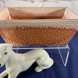 May include: A rectangular ceramic planter with a brown and white glaze. The planter has a textured surface and a white rim.