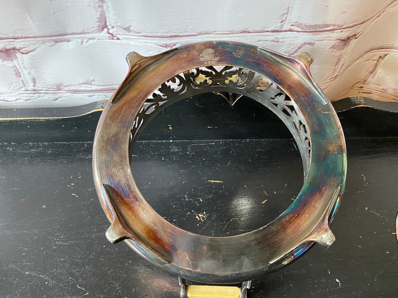 K&ouml;nnte beinhalten: Servierst&auml;nder aus versilbertem Metall mit einem verzierten, durchbrochenen Design. Der St&auml;nder hat vier F&uuml;&szlig;e und eine runde Oberseite.