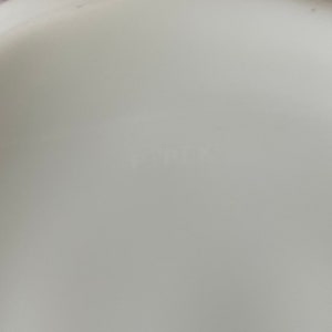 May include: Close-up of the bottom of a white ceramic bowl with the word "Fiesta" printed in black.