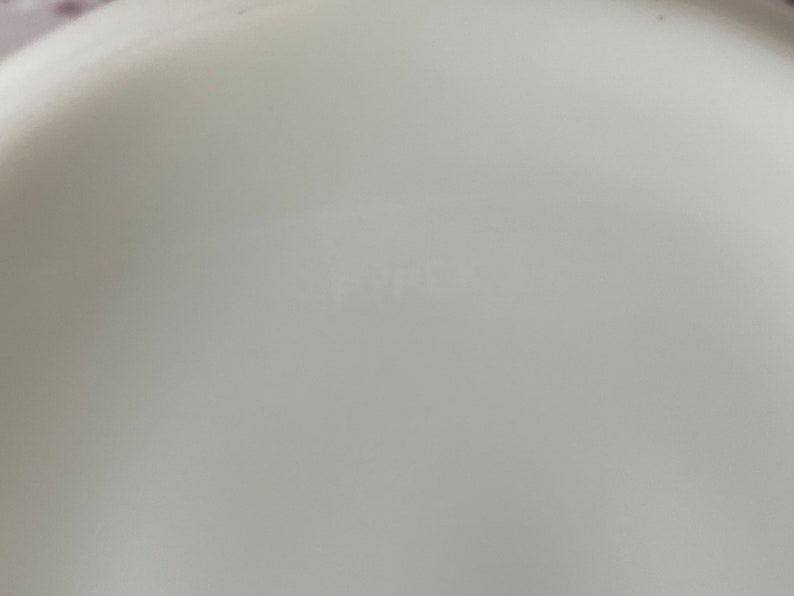 May include: Close-up of the bottom of a white ceramic bowl with the word "Fiesta" printed in black.