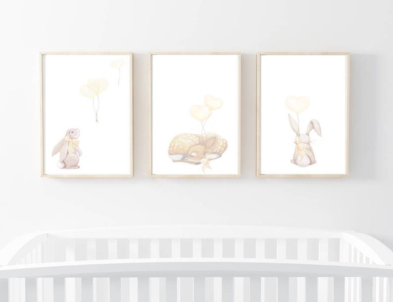 May include: Three framed wall art prints featuring watercolor illustrations of a rabbit, a sleeping fawn, and a rabbit holding a heart-shaped balloon. Each print uses a soft palette of cream, beige, and pale yellow on a white background.