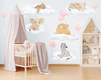 May include: A wall decal set featuring watercolor illustrations of a tiger, elephant, giraffe, and zebra resting on white clouds, accented by pink balloons, displayed on a nursery wall behind a white crib and a wooden house-shaped shelf.