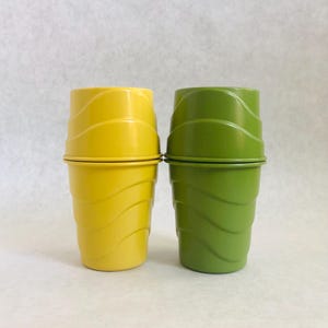 Puede incluir: Dos vasos de pl&aacute;stico, uno amarillo y otro verde, est&aacute;n apilados. Los vasos tienen un dise&ntilde;o acanalado alrededor del cuerpo y una tapa a juego. El vaso amarillo est&aacute; a la izquierda y el verde a la derecha.