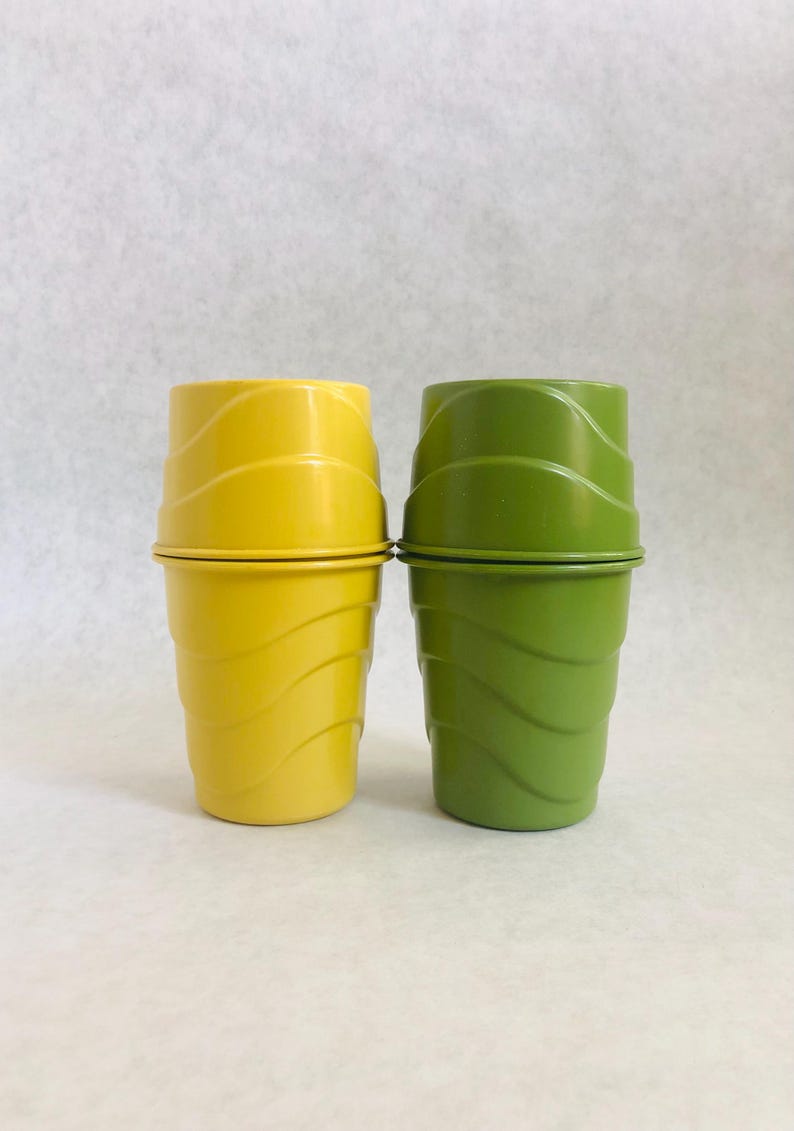 Puede incluir: Dos vasos de pl&aacute;stico, uno amarillo y otro verde, est&aacute;n apilados. Los vasos tienen un dise&ntilde;o acanalado alrededor del cuerpo y una tapa a juego. El vaso amarillo est&aacute; a la izquierda y el verde a la derecha.