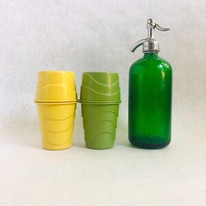 Puede incluir: Un juego de bar vintage con una botella de seltz de vidrio verde con una parte superior cromada y dos juegos de vasos de pl&aacute;stico amarillos y verdes. Las tazas tienen un dise&ntilde;o acanalado. La botella de seltz mide aproximadamente 30 cm de alto.