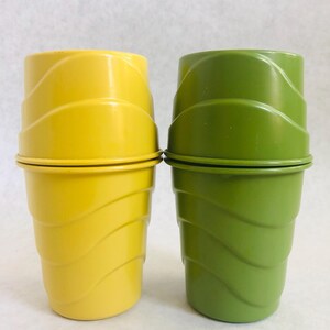 Puede incluir: Dos vasos de pl&aacute;stico, uno amarillo y otro verde, est&aacute;n apilados. Los vasos tienen un dise&ntilde;o ondulado en los lados y un borde plano. El vaso amarillo est&aacute; a la izquierda y el vaso verde a la derecha. El fondo es blanco.
