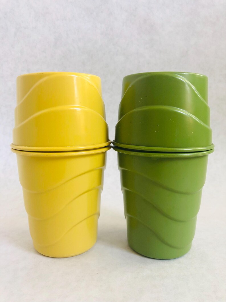 Puede incluir: Dos vasos de pl&aacute;stico, uno amarillo y otro verde, est&aacute;n apilados. Los vasos tienen un dise&ntilde;o ondulado en los lados y un borde plano. El vaso amarillo est&aacute; a la izquierda y el vaso verde a la derecha. El fondo es blanco.