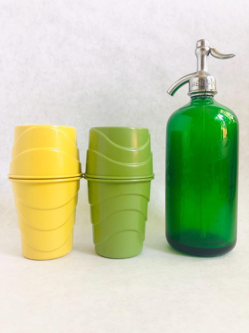 Puede incluir: Un vaso de helado amarillo y otro verde con tapas, junto a una botella de sif&oacute;n de vidrio verde con una boquilla plateada. Los vasos tienen un dise&ntilde;o acanalado. La botella de sif&oacute;n es de color verde vibrante.