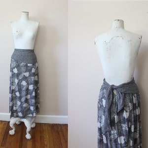 May include: A long, flowing skirt with a gray and white floral pattern. The skirt has a wide, dotted waistband and is displayed on a mannequin. The skirt is made of a lightweight fabric, perfect for a casual, bohemian look.