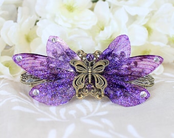 May include: Purple glitter butterfly hair clip with a bronze butterfly design and clear rhinestones.