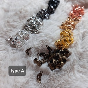 Op de afbeelding: Assortiment van metalen sluitingen in verschillende kleuren, waaronder zilver, goud, brons en zwart. De sluitingen zijn klein en hebben een afgeronde vorm. De tekst "type A" is zichtbaar in de afbeelding.