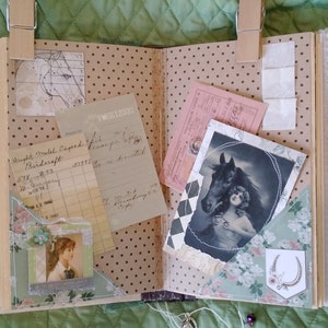 Puede incluir: &Aacute;lbum de recortes abierto con efem&eacute;rides vintage, que incluyen un retrato de caballo, recibos y un retrato de mujer. Las p&aacute;ginas tienen un patr&oacute;n de lunares y detalles florales. El encaje y las pinzas de madera a&ntilde;aden un toque decorativo.