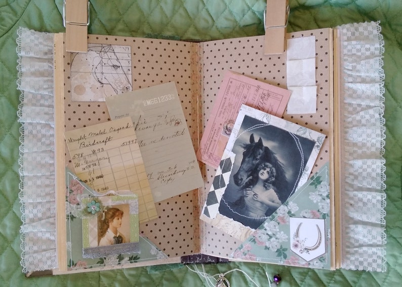 Puede incluir: &Aacute;lbum de recortes abierto con efem&eacute;rides vintage, que incluyen un retrato de caballo, recibos y un retrato de mujer. Las p&aacute;ginas tienen un patr&oacute;n de lunares y detalles florales. El encaje y las pinzas de madera a&ntilde;aden un toque decorativo.