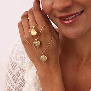 May include: Three gold necklaces with different locket pendants. The lockets are a heart, a circle, and an oval. Each locket has a small diamond-like stone in the center.