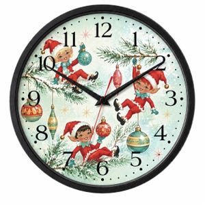 Könnte beinhalten: Eine runde Wanduhr mit schwarzem Rahmen und hellblauem Hintergrund, die drei Elfen in roter Kleidung und Mützen zeigt, die mit Weihnachtsschmuck und Tannenzweigen spielen. Das Zifferblatt zeigt schwarze Zahlen von 1 bis 12 und schwarze Zeiger.