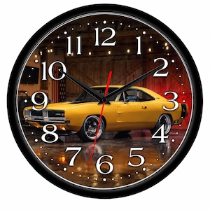 May include: A round wall clock with a black frame featuring a yellow muscle car on the face. The clock has white numbers from 1 to 12, black hour and minute hands, and a thin red second hand. The background shows a garage setting with lights.