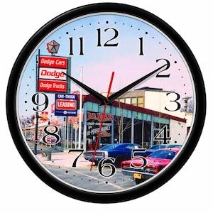 May include: A round wall clock with a black frame featuring a vintage photograph of a Dodge dealership. The clock face displays black numbers, black hour and minute hands, and a red second hand. Text includes Dodge Cars, Dodge, Dodge Trucks, Car-Truck Leasing, and Mr. Norm's Hi-Performance Cars.