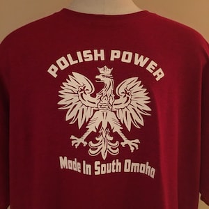 May include: Red t-shirt with a white graphic of a Polish eagle with a crown and the text "Polish Power" above and "Made in South Omaha" below.