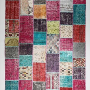 Puede incluir: Una alfombra de patchwork colorida con una variedad de patrones y colores, incluyendo rosa, azul, verde y marrón. La alfombra está hecha de materiales reciclados y tiene un aspecto único y hecho a mano.